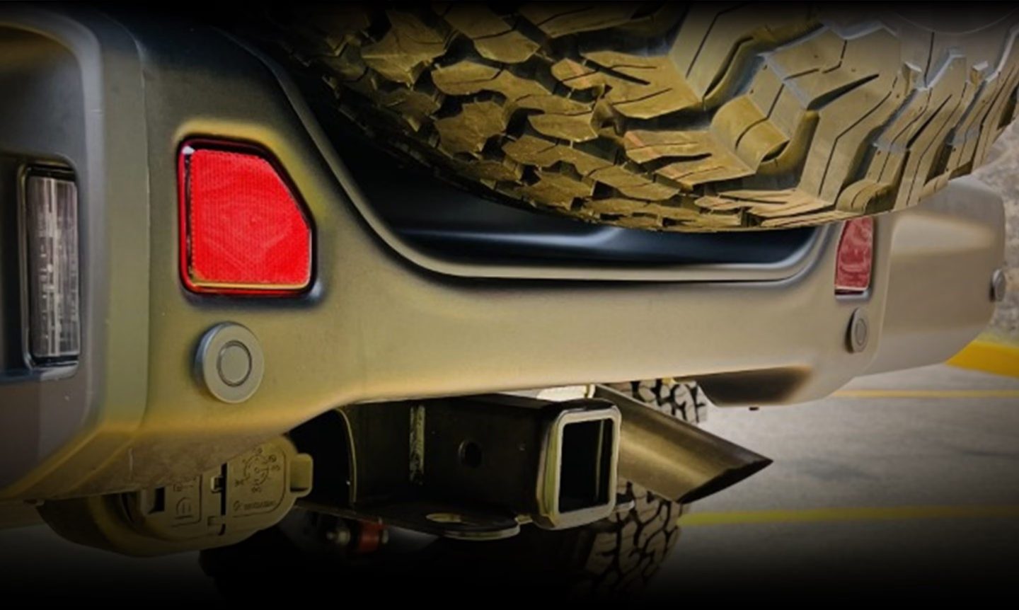 A passenger-side profile of a 2024 Jeep Wrangler Rubicon 392, with its doors removed and its sunroof opened, positioned directly over a deep crevice created by two boulders. 392.